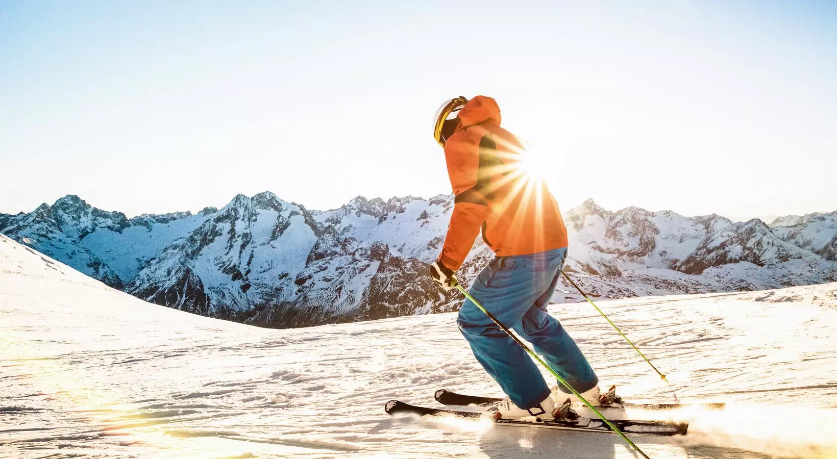 Professional skier athlete skiing at sunset on top of french alps ski resort - Winter vacation and sport concept with adventure guy on mountain top riding down the slope - Warm bright sunshine filter